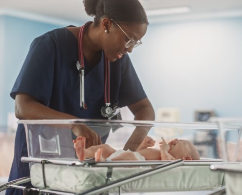 An image of a nurse caring for a newborn baby in a hospital cot