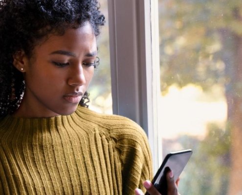 An image of a woman looking at her mobile at home