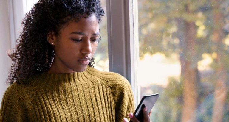 An image of a woman looking at her mobile at home