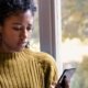 An image of a woman looking at her mobile at home