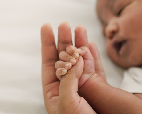 An image of a baby holding someone's hand