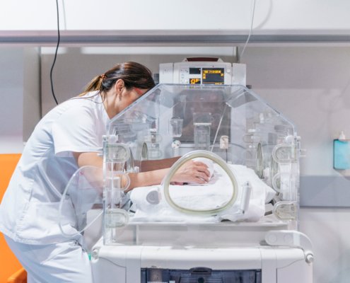 Female doctor examining baby in incubator