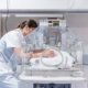 Female doctor examining baby in incubator